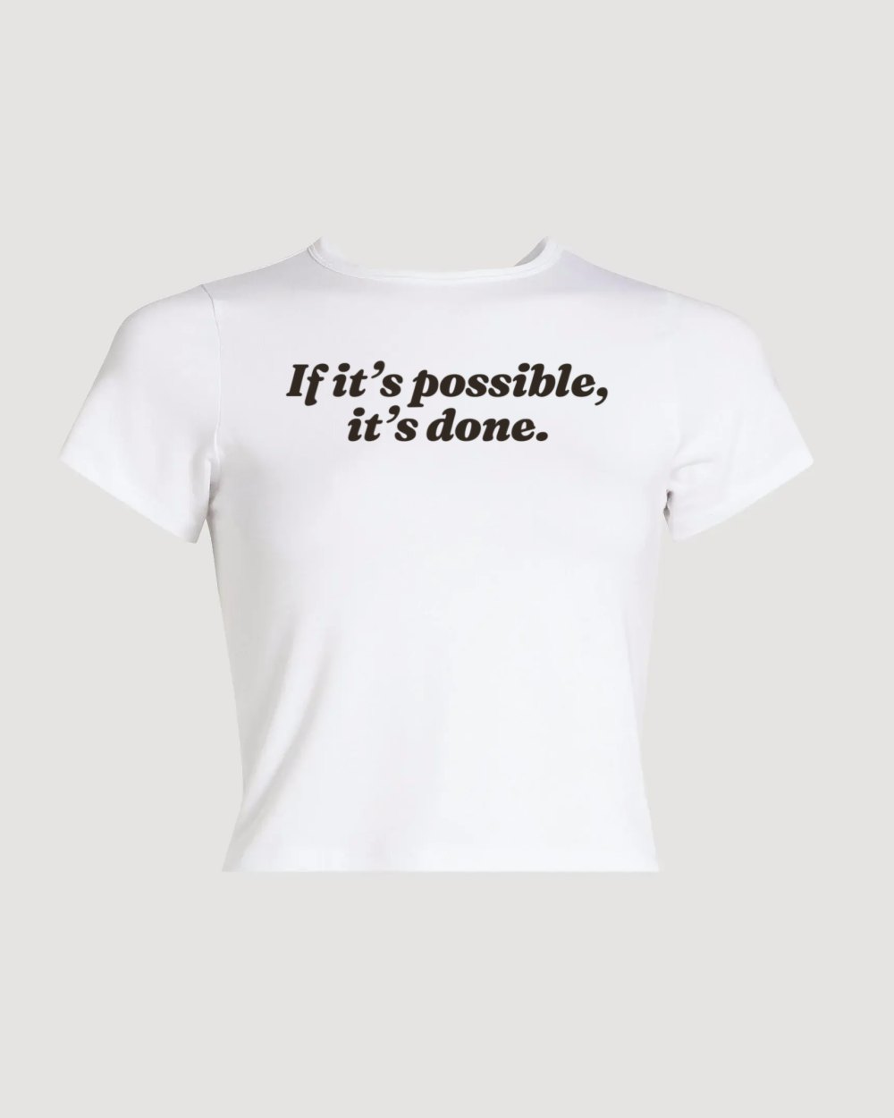 White baby tee printed with If it's possible, it's done.